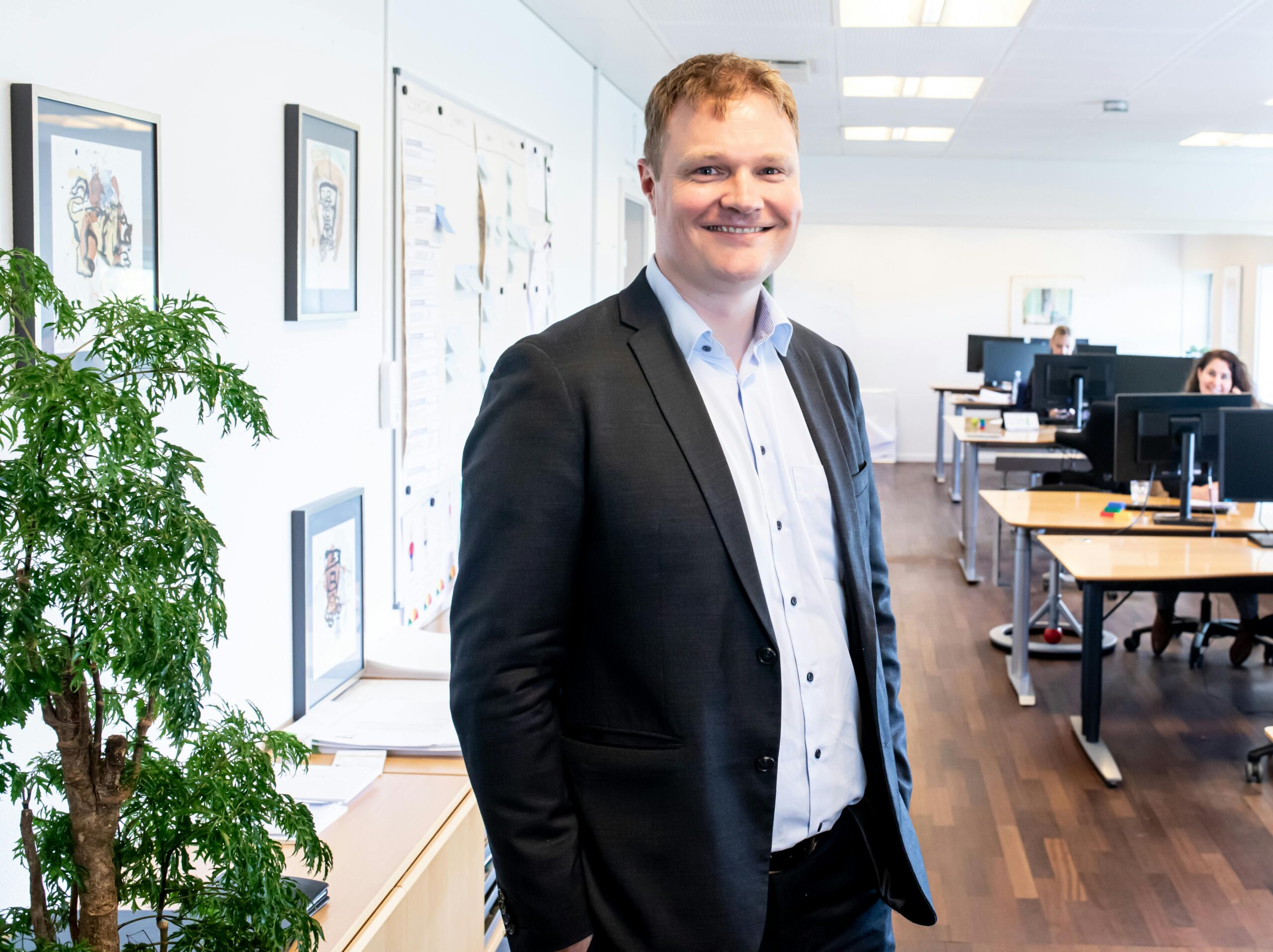 Smiling businessman standing confidently in a bright, modern office setting.
