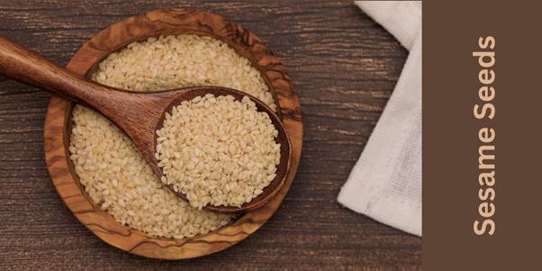 White sesame seeds in a wooden bowl with wooden spoon.