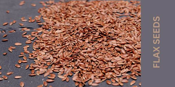 Brown flax seeds in a gray background.